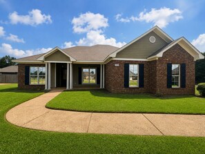 A two-story house with a brick exterior, a front porch, and a well-maintained lawn.