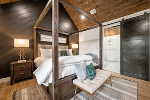 Un lit à baldaquin, une table de chevet, un banc et une lampe fixée au mur.