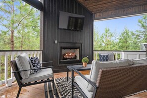 Une terrasse extérieure dotée d’une cheminée, d’un espace salon et d’un téléviseur fixé au mur.