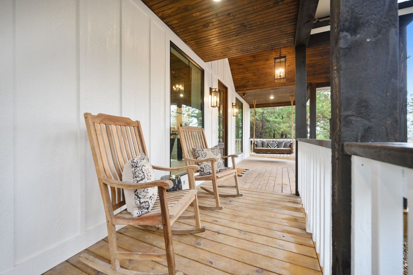 A wooden porch with two rocking chairs and a swing.