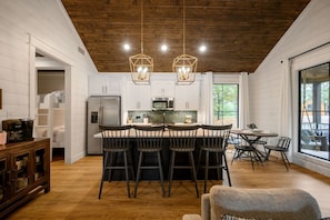 Une cuisine moderne dotée d’un îlot central, d’un plafond en bois et de grandes fenêtres.