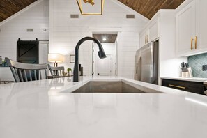 Une cuisine moderne avec des meubles blancs, un robinet noir et un réfrigérateur en acier inoxydable.