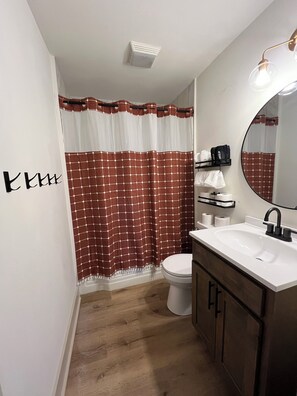 Un baño con inodoro, lavamanos y cortina de ducha.
