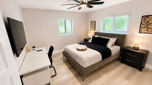 A modern bedroom with a bed, bedside tables, a desk, and a ceiling fan. - The Lincoln Luxe • Midtown Tampa •Near Downtown • Raymond James Stadium• Airport (Tampa)
