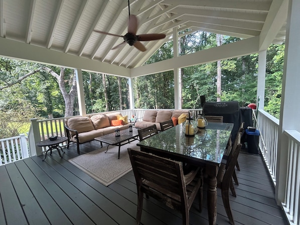 A covered outdoor deck with a dining table, chairs, and a sofa.