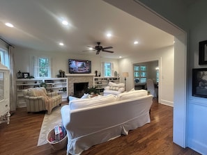 A living room with a fireplace, a television, and a ceiling fan.