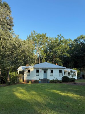 Ein Bungalow mit Veranda, Vorgarten und blauem Himmel.