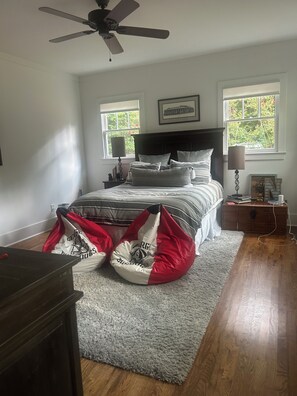 Ein Schlafzimmer mit einem Bett, zwei Nachttischlampen, einem Deckenventilator, einem Fenster und einem Teppich.