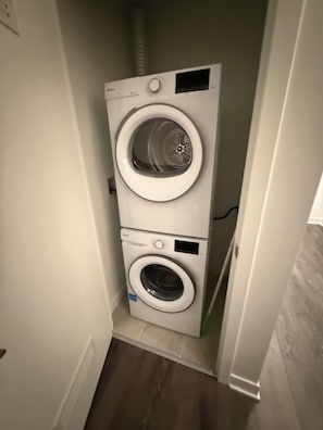 A compact, two-door washer and dryer unit in a narrow hallway.