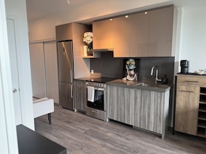 A modern kitchen with a stainless steel refrigerator, double oven, and a wooden countertop.