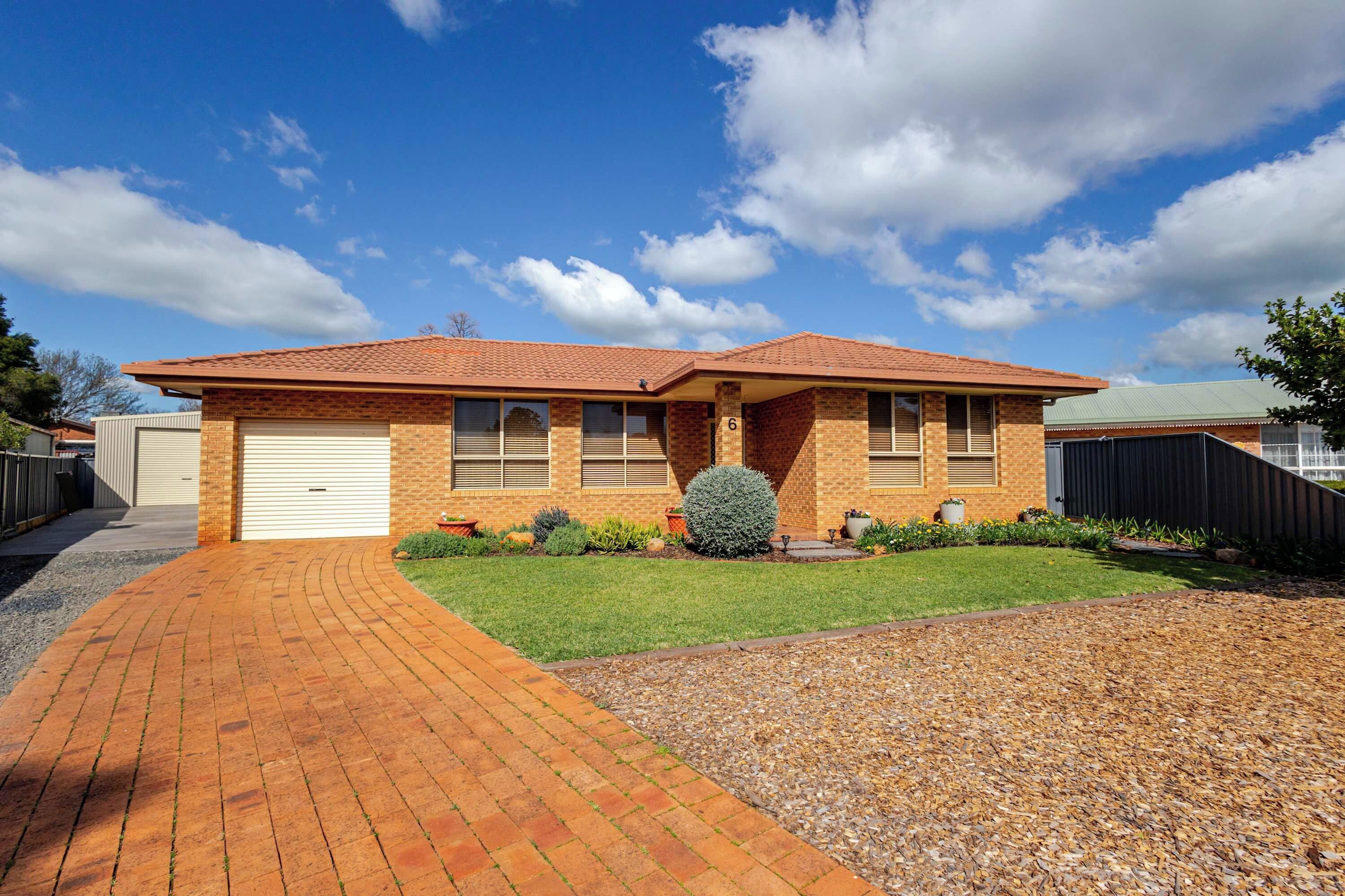 A two-story house with a brick facade, a garage, and a well-maintained lawn.