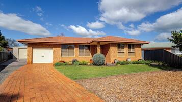 A two-story house with a brick facade, a garage, and a well-maintained lawn.