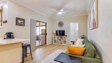 A living room with a sofa, a coffee machine, a TV, and a ceiling fan.