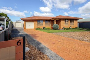A two-story house with a brick exterior, a driveway, and a well-maintained lawn. - House of Tudor II, Dubbo (Dubbo)