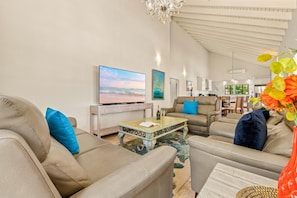 A spacious living room with a flat-screen TV, comfortable seating, a chandelier, and artwork on the walls. - 3BD Villa Luma near Palm Beach and Ritz - Pool/BBQ (Noord)