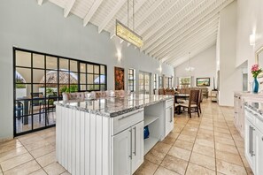 A spacious kitchen with a large island, white cabinetry, and a view through a glass door to an outdoor area. - 3BD Villa Luma near Palm Beach and Ritz - Pool/BBQ (Noord)