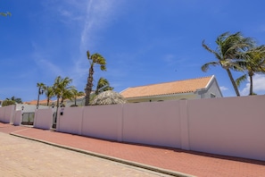 A coastal property with a white wall, a red brick pathway, and palm trees. - 3BD Villa Luma near Palm Beach and Ritz - Pool/BBQ (Noord)