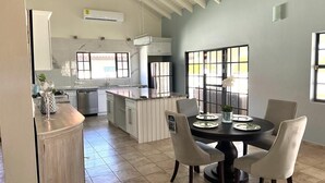 A spacious kitchen with a dining area, featuring a large island, white cabinetry, and a view through the windows. - Renovated 3BR Home Private PoolClose 2 BeachBBQ (Noord)