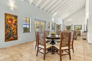 Un coin repas avec une table ronde, des chaises et un panier de fruits.