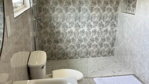 A bathroom with a bathtub, toilet, and shower area. - Renovated 3BR Home Private PoolClose 2 BeachBBQ (Noord)