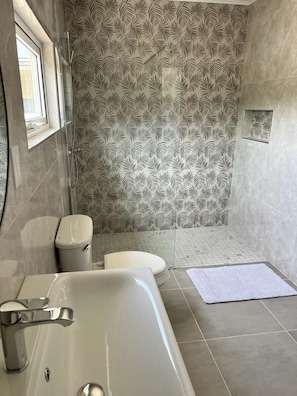 Ein Badezimmer mit Badewanne, Toilette und Duschbereich.