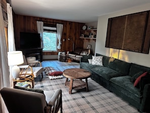 A living room with a sofa, a coffee table, a TV, and a window with curtains.