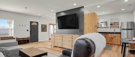 A modern living room with a flat-screen TV, a sofa, a coffee table, and a fireplace.