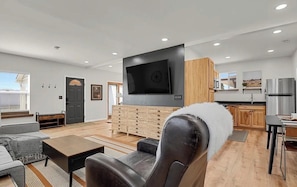 A modern living room with a flat-screen TV, a sofa, a coffee table, and a fireplace.