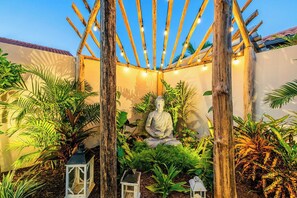 A serene garden with a Buddha statue, wooden pergola, and lanterns. - Villa Prikichi II ~ Close to Beach w/ Private Pool (Noord)