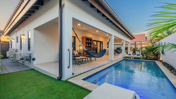 Una casa moderna con piscina, area relax all'aperto e un'amaca.