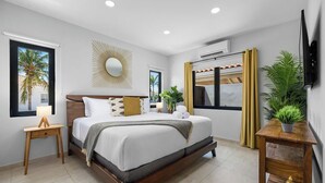 Una camera da letto moderna con un letto grande, comodini, una TV a parete e una finestra con tende.