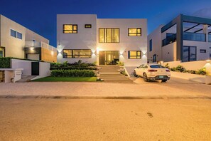 Een modern huis met twee verdiepingen, met een auto op de oprit.