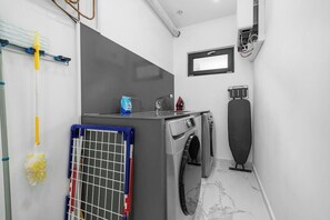 A compact laundry room with a washing machine, dryer, and ironing board.