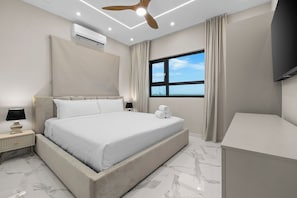 Een moderne hotelkamer met een groot bed, een plafondventilator, een airconditioning, een televisie en een raam met uitzicht.