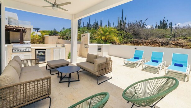 Un patio exterior con una parrilla, asientos y sillones.