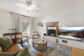 A living room with a fireplace, a television, and a sofa. - Entire Home-Charming Historic Adobe Prime Location (Santa Fe)