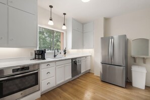 A modern kitchen with white cabinets, stainless steel appliances, a built-in oven, and a refrigerator. - Entire Home-Charming Historic Adobe Prime Location (Santa Fe)