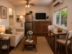 A compact living space with a kitchenette, a dining area, and a seating area with a sofa and chairs.