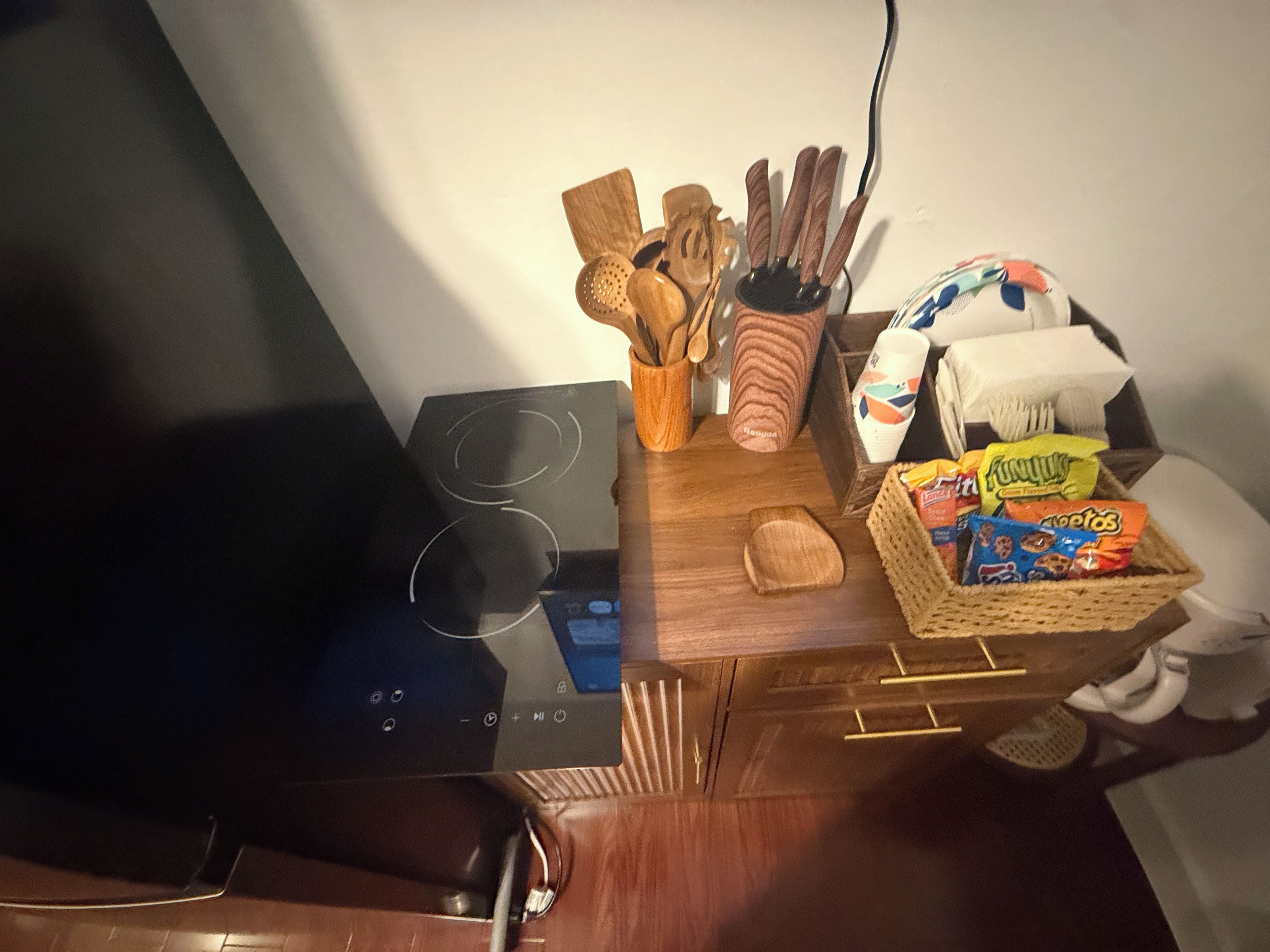 Ett kök med en spis, träredskap, en korg med snacks och ett eluttag.