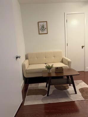 A living room with a sofa, a coffee table, a potted plant, and a framed picture on the wall. - House of VANTA on Fifteenth (Miami)