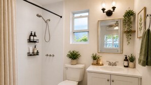 A bathroom with a shower, toilet, sink, and a window.