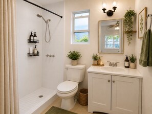 A bathroom with a shower, toilet, sink, and a window.
