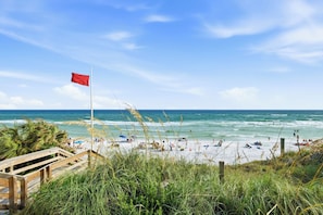 Ein Strand mit einer Flagge, Blick auf den Ozean und Menschen.