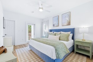 Ein Schlafzimmer mit einem Bett, einem Nachttisch, einem Deckenventilator und zwei an der Wand hängenden Bildern.
