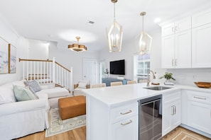 A modern kitchen with white cabinetry, a central island, and pendant lighting. - Sunnyside - 30a Blue Mountain Beach -Golf Cart or Walk to Beach With Ease (Santa Rosa Beach)
