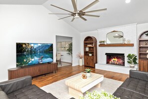 A modern living room with a fireplace, a television, and a ceiling fan. - Lake Norman Private Getaway with Pool, Hot Tub & Game Room (Denver)
