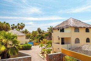 Ein Resort mit strohgedeckten Gebäuden, Palmen und blauem Himmel.
