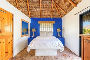 Ein Schlafzimmer mit einem Bett, zwei Nachttischlampen, einem Fenster und einem Holzschrank.
