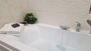 A bathtub with running water, a stack of white towels, and a small potted plant. - Entire property with garden and free parking (Turda)