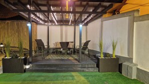 A covered outdoor seating area with a table and chairs, surrounded by planters with greenery. - Entire property with garden and free parking (Turda)
